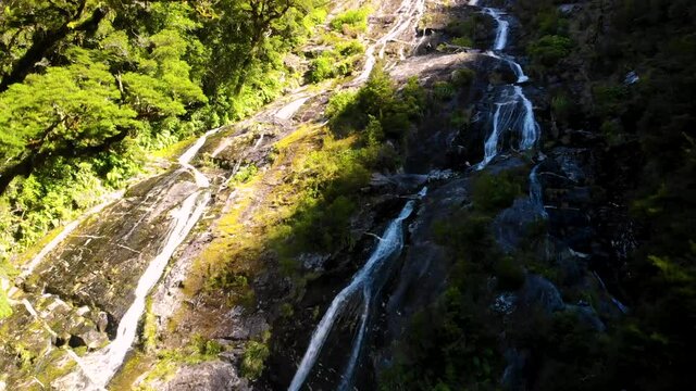 Small Waterfall Cascading Down Mountainside - tilt up wide shot