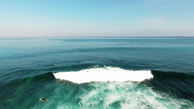 Aerial drone view of a group of surfers and large waves, at Jelenga beach, in Sumbawa