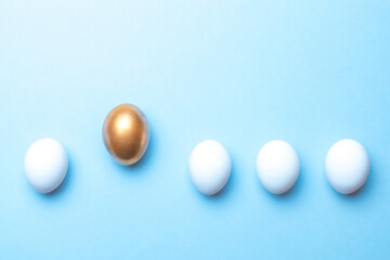 Easter holiday. Golden, white colour egg on pastel blue background in Happy Easter decoration. Spring holiday top view with copy space.