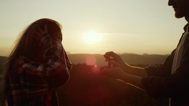 Hikers standing on top of mountain. Smiling man proposing marriage to woman 