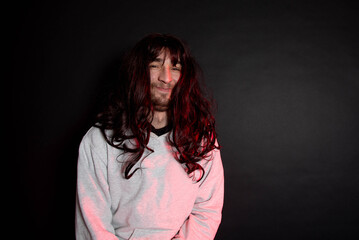 Portrait of young transgender woman on black background. Funny bearder man wearing wig.