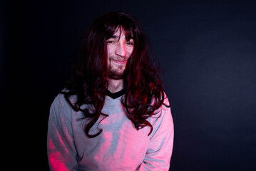Portrait of young transgender woman on black background. Funny bearder man wearing wig.