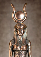 The figure of the Egyptian goddess Isis on a brown corduroy background. Bronze statuette.