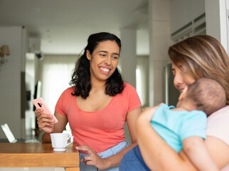 lesbian couple enjoying time together while baby sleeps in the kitchen.