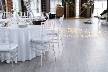Transparent plastic chairs for wedding guests. Modern loft space, large windows.