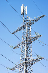 Electricity pole for transportation of electricity with a antenna on top with a clear blue sky