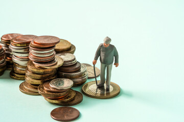 Miniature people stand on coins. Elderly people and their savings, pension