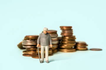 Miniature people stand on coins. Elderly people and their savings, pension