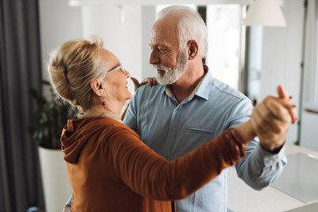 Happy mature couple having fun while dancing at home