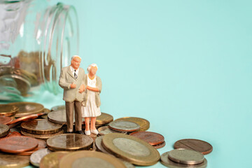Miniature people stand on coins. Elderly people and their savings, pension