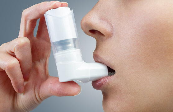 Close-up of woman using medical inhaler to prevent an asthma attack.