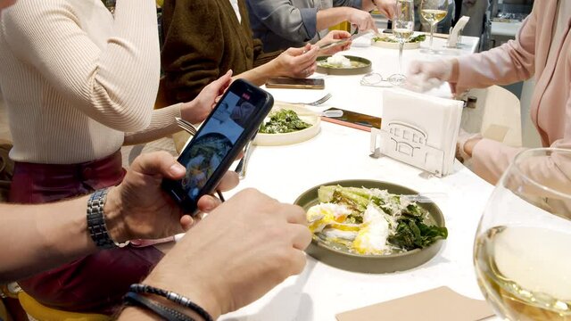 Close-up shot of unrecognizable man videotaping his food using smartphone at a party in a restaurant or cafe. Blogging and social media concept