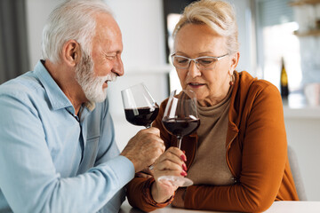 Happy mature couple drinking wine at home