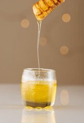 Vertical shot of honey dipping in a transparent glass from a dipper