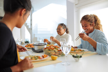 Family of filipino women sharing lunch together at home - Family spending quality time cooking asian food and eating it together - 422830435