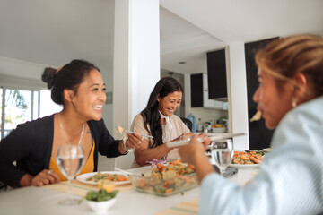 Family of filipino women sharing lunch together at home - Family spending quality time cooking asian food and eating it together - 422830467