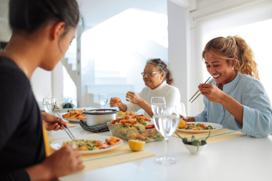 Family of filipino women sharing lunch together at home - Family spending quality time cooking asian food and eating it together
