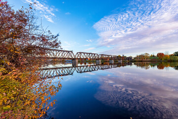 Prince of Wales Bridge, an out of use interprovincial railway bridge in - blue sky and Cirrocumulus clouds reflect on the calm water of the Ottawa River