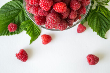 Ripe raspberries with green leaf isolated on white background