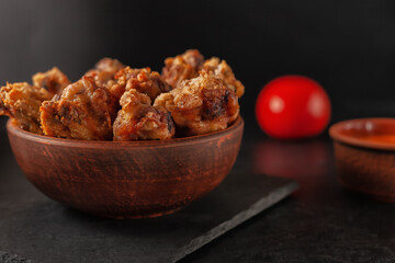 Buffolo wings close-up in ceramic bowl with tomato sauce and tomatoes