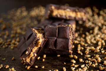 Broken assorted chocolate bar with carrot cake filling with cashew nuts around on a wooden table. Gourmet. Close up.
