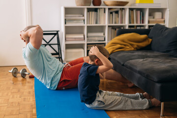 father and son workout training at home. quarantine concept.