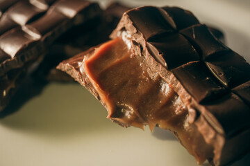Broken assorted chocolate bar with caramel filling on a white plate. Gluten free. Close up....