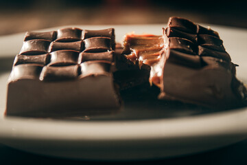 Broken assorted chocolate bar with caramel filling on a white plate. Gluten free. Close up. Gourmet. 