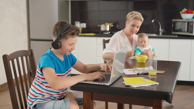 Boy playing on laptop while woman feeding baby
