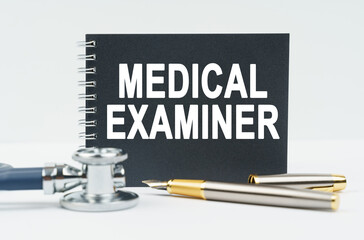 On a white background lies a stethoscope, a pen and a black notebook with the inscription - MEDICAL...