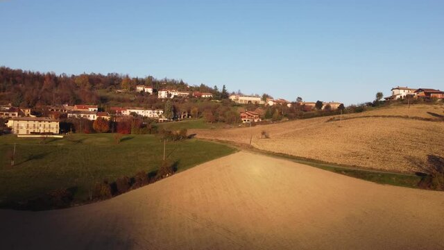 Aerial view of plowed fields and rural villages on the hills of Monferrato, Piedmont, Italy at sunset