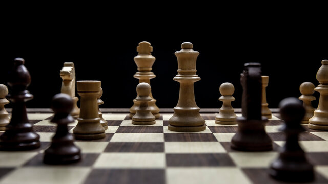 Chessboard with various pieces fighting during a game. Concept picture taken in studio and concerning decision making and strategy.