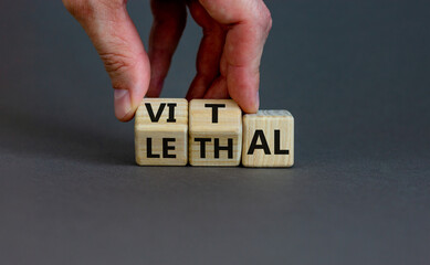 Vital vs lethal symbol. Businessman turns wooden cubes and changes the word 'lethal' to 'vital'. Beautiful grey background, copy space. Business and vital vs lethal concept.