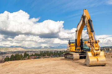 A large excavator sits on a vacant lot on a hilltop overlooking the cities of Spokane Valley and Liberty Lake in Washington State, USA