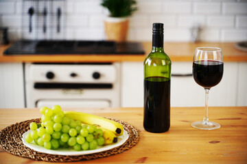 Close up of bottle and glass of red wine with berries and fruits on plate. Preparation on table for...