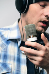 voice recording, a man sings into a condenser microphone