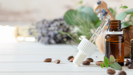 organic cosmetics concept, glass bottle with oil, pipette and lavander flowers, eucaliptus on light wooden background