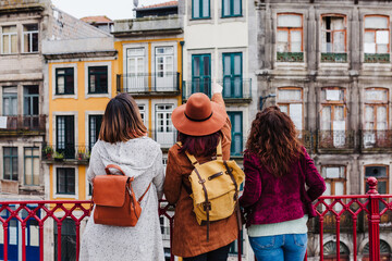 back view of three women sightseeing Porto views by the river. Travel and friendship concept - obrazy, fototapety, plakaty