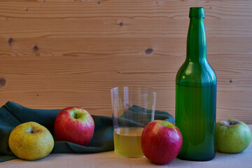 Asturian cider bottle with glass with cider and apples and wooden background