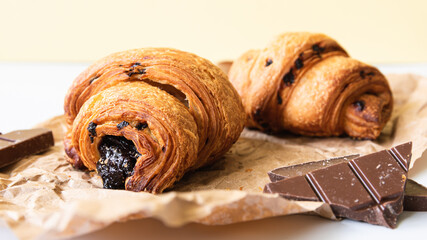 composition, three croissants with chocolate filling on a table on a yellow background