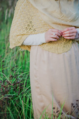 A Muslim woman stands on the field and holds a spike of wheat in her hands. Muslim woman in beige hijab. Beauty, femininity, feminism.