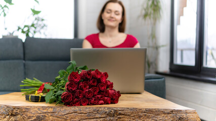 An adult girl writes in an online chat of a dating site. Long-distance romantic relationships during the COVID-19 pandemic. A woman thanks a friend for a gift via video communication on a laptop.