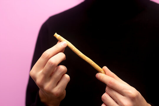 Guy hold miswak. Bokeh effect. Teeth cleaning. Sunnah. Sivak. Pink background.