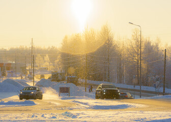 Cars in city outskirts on a bright setting sun on a frosty winter day