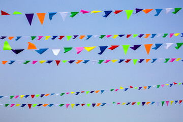 Obraz premium triangular festive multi-colored flags are suspended on a tight rope against the background of the sky, nobody.