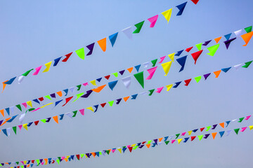 Obraz premium triangular holiday multi colored flags are suspended on a tight string outdoors park against the background of the sky, nobody.