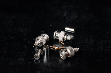 Three main components of a bnc connector close-up. Body, center conductor and crimp on a dark...