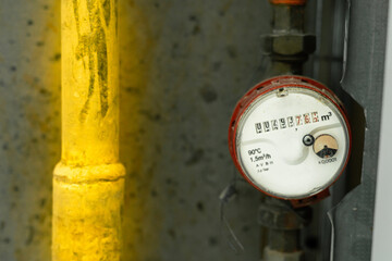 Hot water meter near the hot water pipe close-up