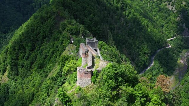 Mount Cetatea, Romania, 21.07.2019. Poenari Castle famous landmark high atop of a mountain. Vlad the Impaler Dracula ancient Citadel, sightseeing surrounded by green trees, sunny day drone shot