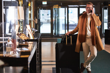 Obraz na płótnie Canvas Businessman in coat goes to reception, arrived in hotel
